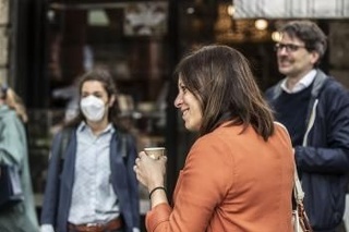 Žena s kávou bez rúška pred barom v Miláne v pondelok 4. mája 2020.