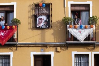 Španielske ženy v tradičnom oblečení spievajú na vyzdobených balkónoch.