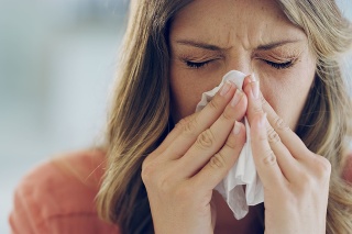 Shot of an attractive young woman feeling ill and blowing her nose with a tissue at home