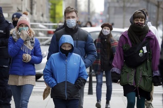 Ľudia sa prechádzajú s rúškami na tvári po ulici v Poľsku. 