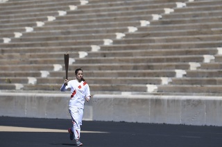 Na snímke olympijská víťazka Katerina Stefanidiová beží s olympijskou pochodňou na prázdnom štadióne kvôli koronavírusu v Aténach počas slávnostného odovzdania olympijskej pochodne pre letné olympijské hry 2020 v Tokiu vo štvrtok 19. marca 2020.