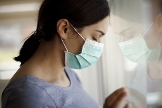 Portrait of sad young woman with face protective mask at hospital