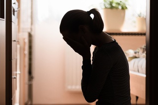 Sad young woman sitting on room floor crying with hand over face