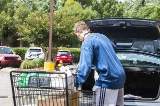 20-05-24 Tulsa OK  Young man wearing mask loads groceries from cart to trunk of car in parking lot during pandemic