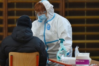 Zdravotníčka v ochrannom odeve odoberá vzorku počas testovania na COVID-19 v Trnave. 