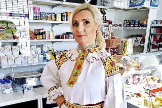 Majiteľka Slávka v pestrom kroji pri otváraní obchodíka.