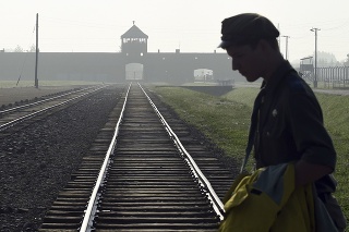 Na archívnej snímke z 29. júla 2016 muž prechádza cez koľajnice, ktoré vedú do bývalého nacistického tábora smrti Auschwitz-Birkenau.