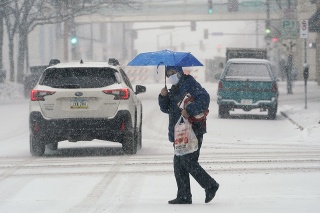 Chodkyňa prechádza cez cestu počas hustého sneženia v centre mesta Des Moines, americký štát Iowa