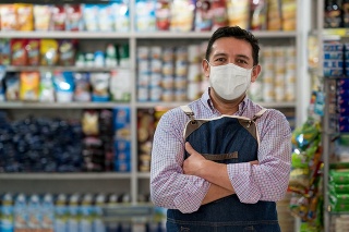 Business owner working at a grocery store wearing a facemask to avoid the coronavirus - pandemic lifestyle concepts