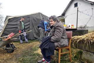 Žena sedí vo svojom dvore pred stanom v chorvátskej Majskej Poljane.