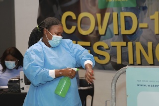 Zdravotníčka v Afrike si dezinfikuje ruky po testovaní na COVID-19.