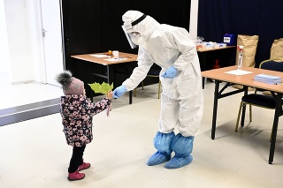 Dievčatko podáva list zdravotníčke počas príchodu na testovanie do divadelnej sály, v ktorej prebieha testovanie v meste Púchov.