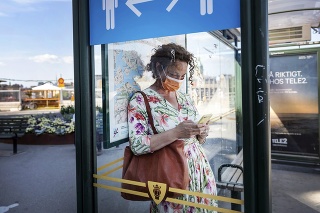 Žena s rúškom na zastávke v Štokholme