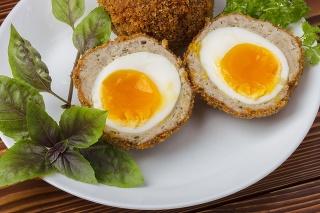 Cooked scottish eggs on white porcelain plate close up