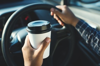 Man holding coffee paper cup in car