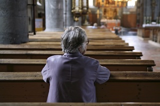 Older woman praying in an almost empty church. Shallow DOF, focus is on the woman