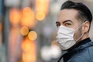 A man is covering covering his mouth and nose with a pollution mask to protect himself from coronavirus, cold virus, flu virus, pollution.