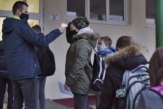Pracovník školy pri meraní teploty žiakovi pred Základnou školou na Námestí Slovenského učeného tovarišstva v Trnave.