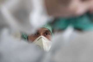 Zdravotník v ochrannom odeve pred ošetrením pacientov s ochorením Covid-19.