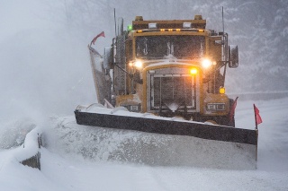 Truck plowing snow off the road at night.