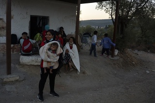 Utečenci a migranti sa zhromaždili pred opustenou budovou počas požiaru, ktorý zachvátil preplnený utečenecký tábor Moria.