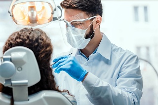 Dentist working in dental clinic with patient in the chair.