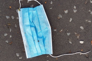 Close-up of a discarded single-use facemask littering a pavement in the UK.