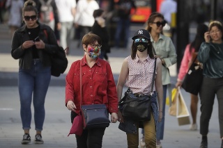 Ľudia s rúškami na tvárach sa prechádzajú po Oxford Street v Londýne. 
