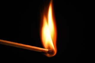 Fire burning on matchstick. Isolated on black background. Macro