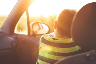 Boy on front seat of a car looking at camera in sunset