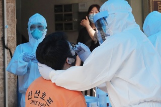 Zdravotník v ochrannom obleku odoberá mužovi vzorku na ochorenie Covid-19 v Soule.