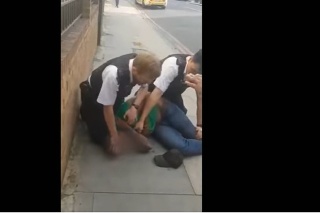 Policajti držia na zemi zatýkaného muža, ktorý kričí, aby mu pustili krk.