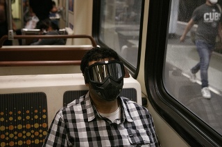 Mladý muž sa chráni rúškom a okuliarmi počas cesty vlakom v Kalifornii. 