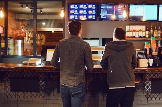 Rear view. Two men choose food in a fast food restaurant. Bar snack concept .