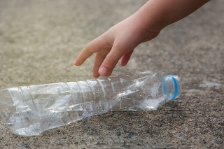Kid hand picking up a waste plastic drinking bottle