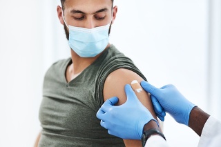 Shot of a doctor applying a band aid after injecting a patient in his arm during a consultation at a clinic