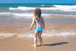 Little girl standing on the beach looking to the ocean