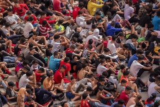 Maloletí migranti bez sprievodu sedia pred skladom používaným ako dočasný prístrešok v španielskej enkláve Ceuta