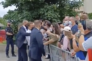 Na videosnímke francúzsky prezident Emmanuel Macron (uprostred) dostáva facku od muža (v zelenom tričku) počas Macronovej návštevy  v obci Tain-l'Hermitage.