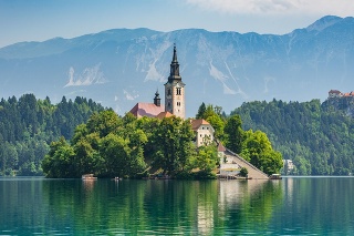 Beautiful Lake Bled in Slovenia. 'Church dedicated to the Assumption of Mary' - Santa Maria Church with surrounding houses and clock tower in the middle of small islet in the famous slovenian lake. Alps in the background. Lake Bled, Slovenia, Europe