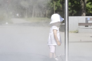 Dieťa prechádza hmlovou bránou počas horúceho letného dňa.