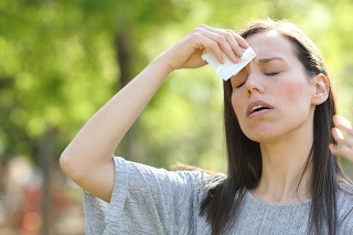 Woman drying sweat using a wipe in a warm summer day