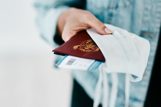 Cropped shot of a woman holding her passport, mask and boarding pass in an airport