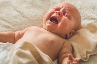 Crying hungry newborn baby lying on the bed. Love baby. Newborn baby and mother.