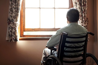 Rearview shot of a senior man looking out the window while sitting in his wheelchair