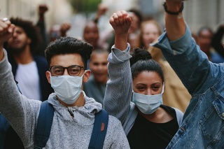 Group of people wearing face mask protesting and giving slogans in a rally. Group of demonstrators protesting in the city.