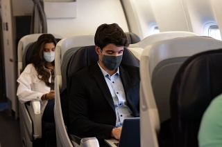 Business man traveling and wearing a facemask on the plane while using his laptopâ COVID-19 pandemic lifestyle concepts