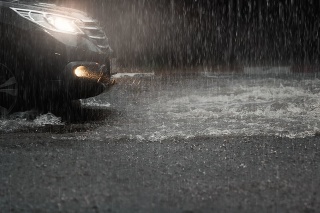 Car with headlights run through flood water after hard rain fall at night.Rainy season.