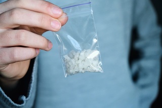 hand holds packet with white narcotic - cocaine, meth or another drug closeup