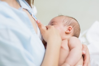 Mother breastfeeding a new born baby boy in a hospital room